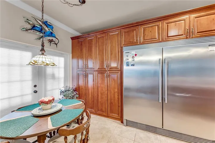 Kitchen with decorative light fixtures, stainless steel built in fridge, ornamental molding, and light tile patterned flooring