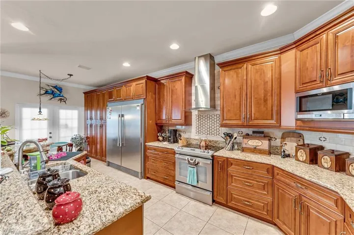 Kitchen with backsplash, sink, wall chimney range hood, built in appliances, and ornamental molding