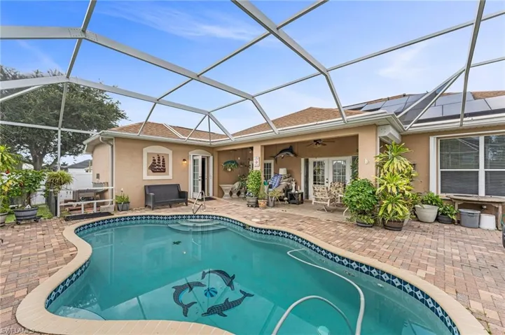 View of pool featuring glass enclosure, french doors, ceiling fan, and a patio