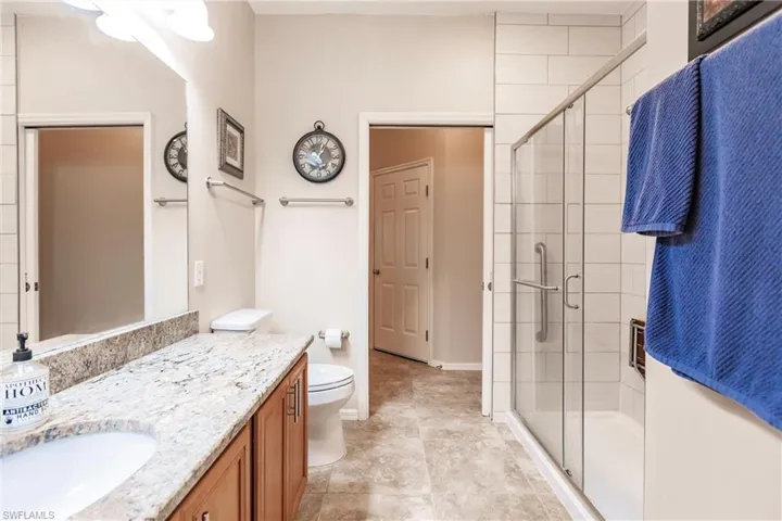 Bathroom featuring tile floors, a shower with door, toilet, and vanity