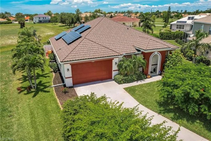 View of front of home featuring a front yard, a garage, and solar panels