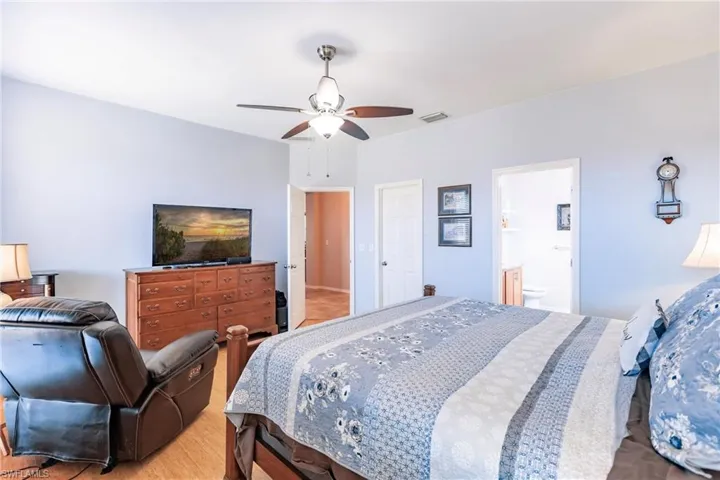 Bedroom featuring wood-type flooring, ensuite bathroom, and ceiling fan