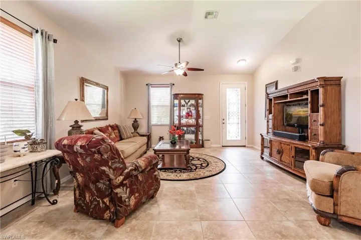 Tiled living room with lofted ceiling and ceiling fan