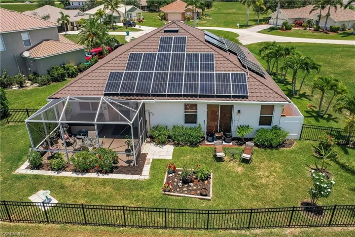 Back of house featuring a lawn and solar panels