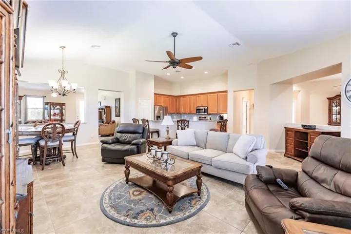 Tiled living room featuring ceiling fan with notable chandelier
