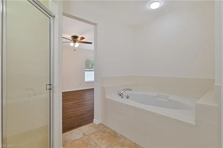Bathroom with tile floors, independent shower and bath, and ceiling fan