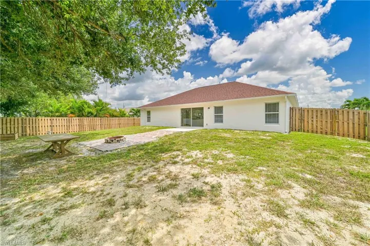 Back of house with a patio area, a fire pit, and a yard