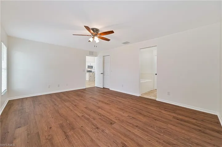Empty room with ceiling fan and dark hardwood / wood-style floors