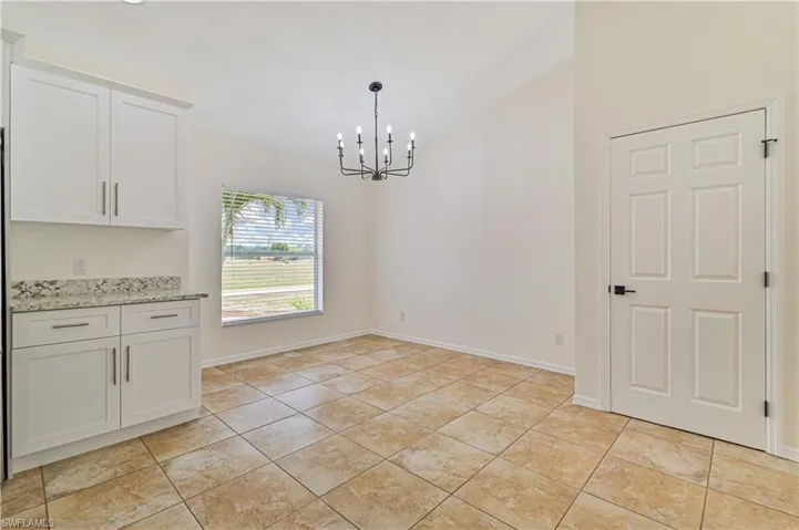 Unfurnished dining area with a chandelier and light tile floors