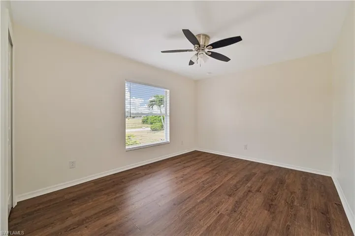 Unfurnished room featuring ceiling fan and dark wood-type flooring