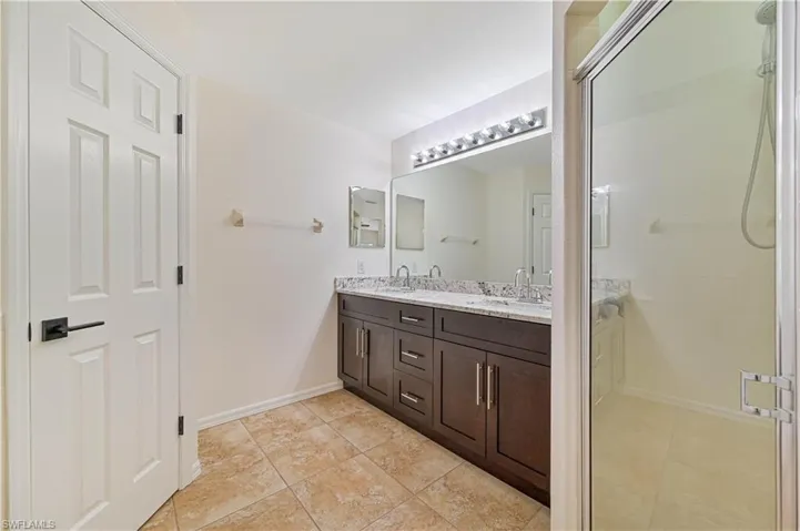 Bathroom with tile flooring, an enclosed shower, and double vanity