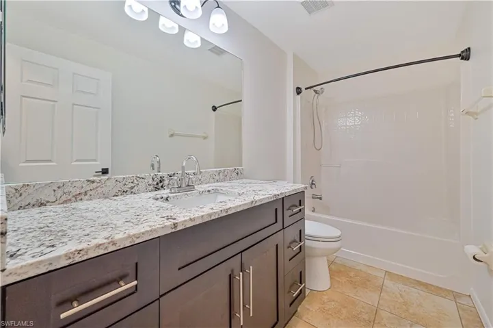 Full bathroom with tile floors, vanity, toilet, and bathtub / shower combination