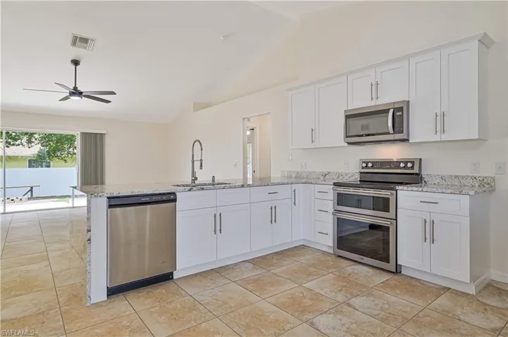 Kitchen with stainless steel appliances, kitchen peninsula, lofted ceiling, and sink
