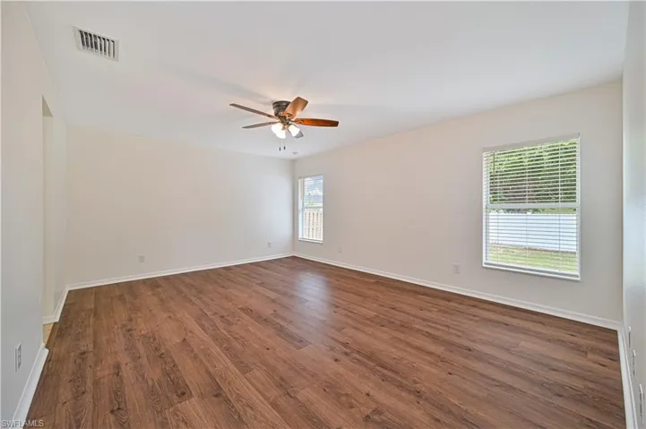 Spare room with a wealth of natural light, dark wood-type flooring, and ceiling fan
