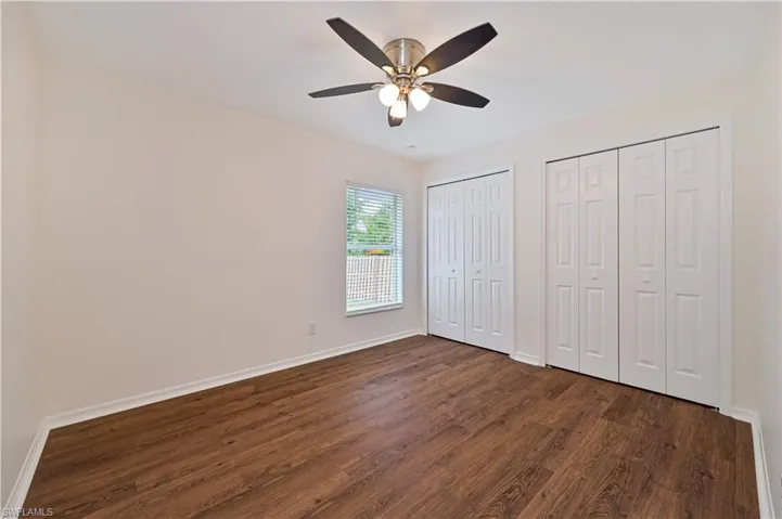 Unfurnished bedroom featuring multiple closets, dark wood-type flooring, and ceiling fan