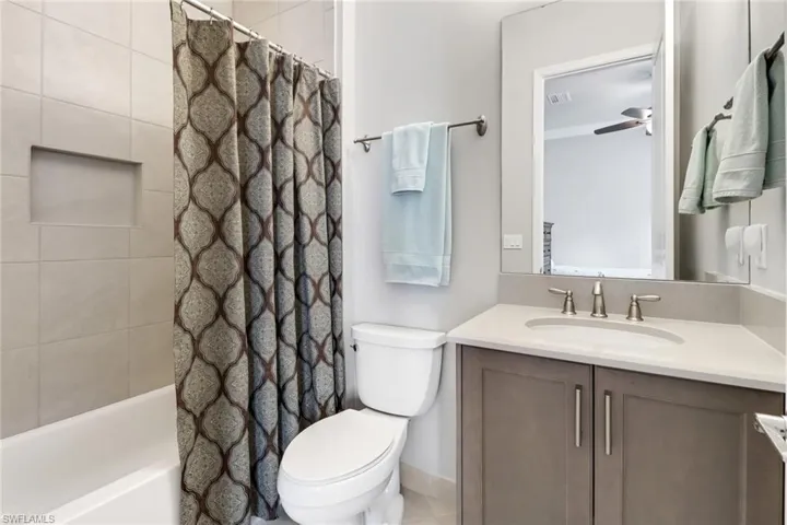Full bathroom featuring vanity, shower / tub combo, toilet, tile patterned floors, and ceiling fan