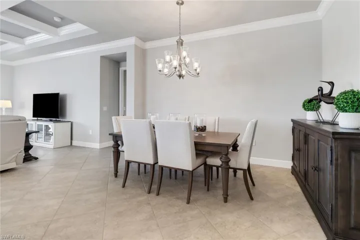 Dining room with ornamental molding, an inviting chandelier, and light tile patterned flooring