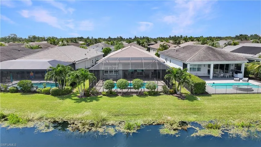 Back of house with a water view, a yard, a patio area, and a lanai