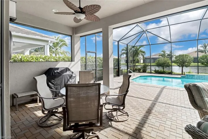 View of swimming pool with area for grilling and ceiling fan