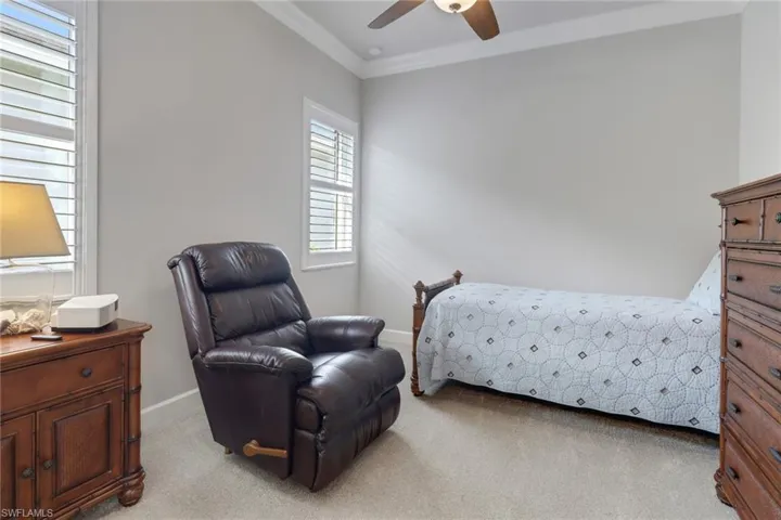 Bedroom with light carpet, crown molding, and ceiling fan