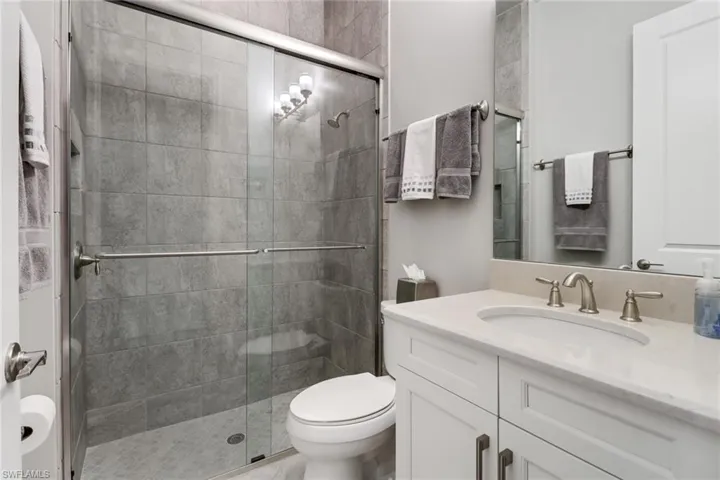 Bathroom with vanity, toilet, and a shower with door
