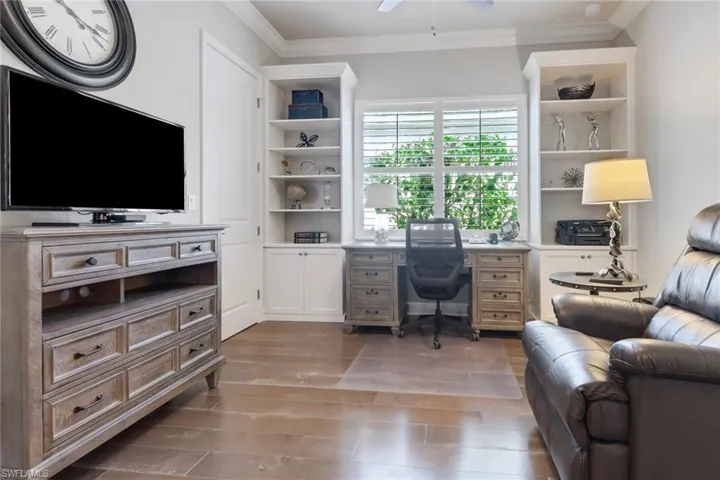 Office with dark wood-type flooring, ceiling fan, and ornamental molding