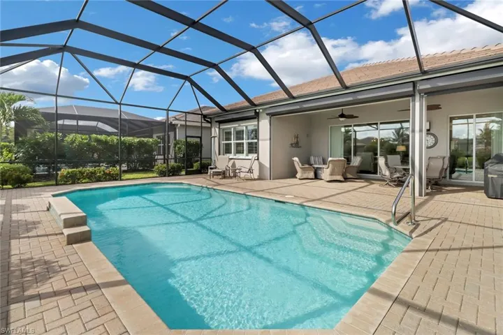 View of swimming pool with a lanai, ceiling fan, and a patio area
