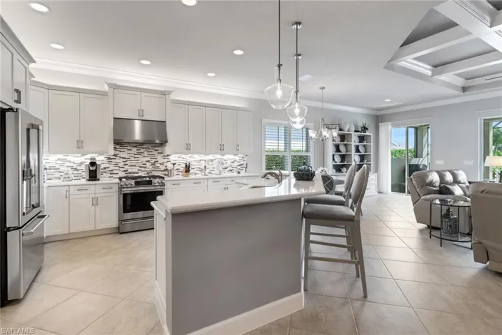 Kitchen with a kitchen island with sink, a kitchen bar, hanging light fixtures, appliances with stainless steel finishes, and light tile patterned flooring