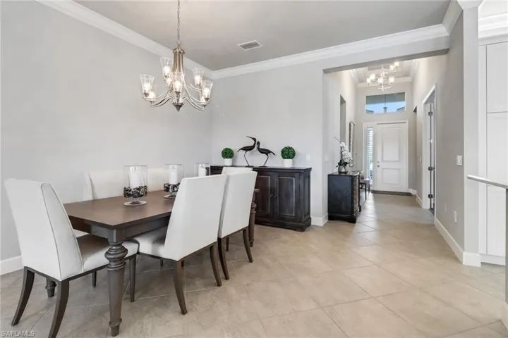 Tiled dining room featuring crown molding and a notable chandelier