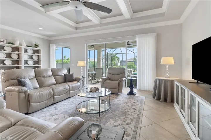 Tiled living room featuring ceiling fan, ornamental molding, beamed ceiling, and coffered ceiling