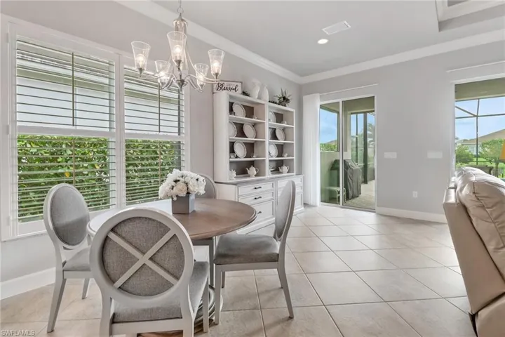 Tiled dining area with a wealth of natural light, a chandelier, and crown molding