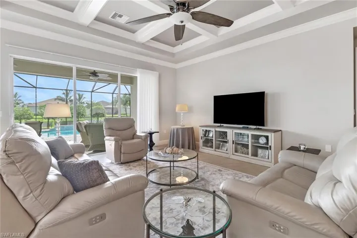 Living room with crown molding, coffered ceiling, ceiling fan, and beamed ceiling