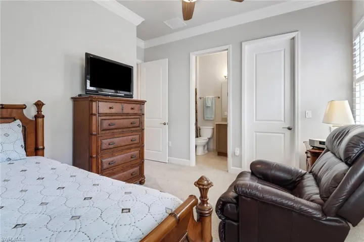 Carpeted bedroom with ceiling fan, ornamental molding, and connected bathroom