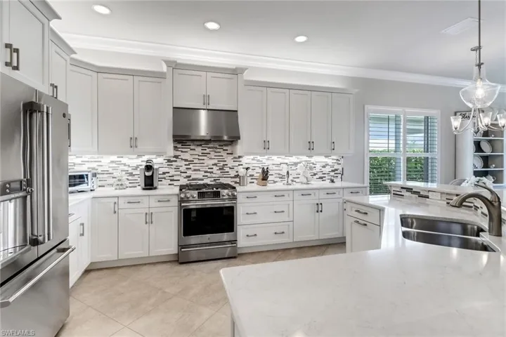 Kitchen with crown molding, stainless steel appliances, sink, pendant lighting, and exhaust hood
