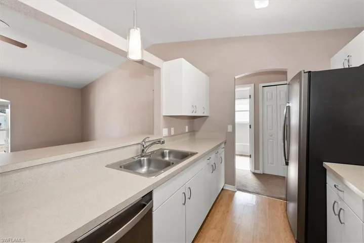 Kitchen with appliances with stainless steel finishes, white cabinetry, light countertops, and decorative light fixtures