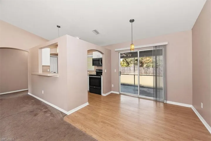 Unfurnished dining area featuring arched walkways, light wood-type flooring, and light colored carpet