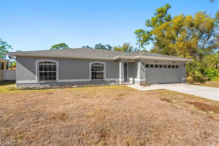 Ranch-style house with stucco siding, driveway, a garage, a front yard, and roof with shingles