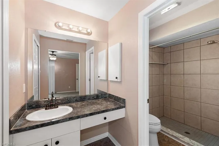 Bathroom with vanity, a shower stall, and a ceiling fan