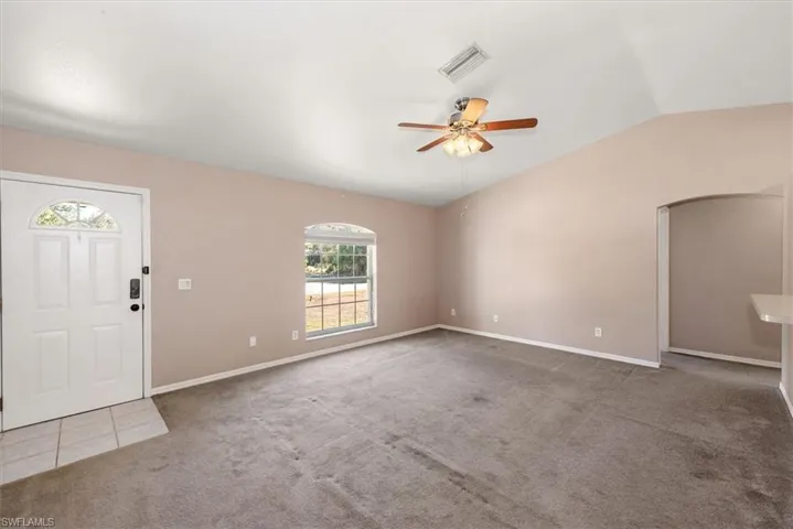 Foyer featuring light carpet, a ceiling fan, vaulted ceiling, and arched walkways