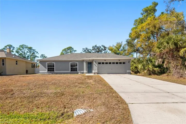 Single story home featuring driveway, an attached garage, stucco siding, and a front lawn