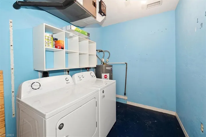 Laundry room featuring washer and dryer, electric water heater, and concrete floors