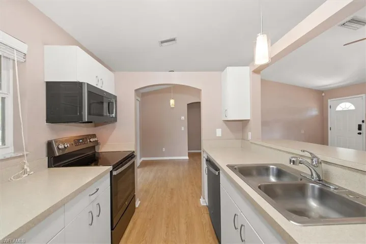 Kitchen featuring hanging light fixtures, stainless steel appliances, and white cabinets