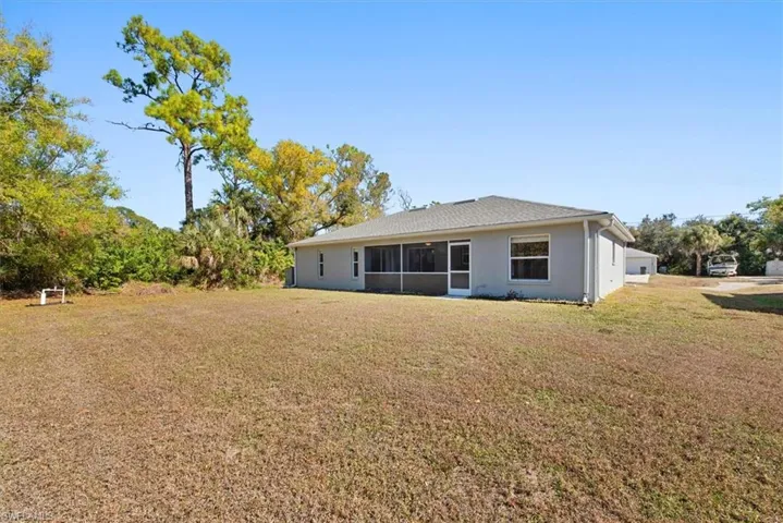 Rear view of property with a yard, a sunroom, and stucco siding