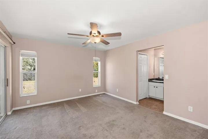 Unfurnished bedroom featuring light colored carpet, a ceiling fan, and connected bathroom