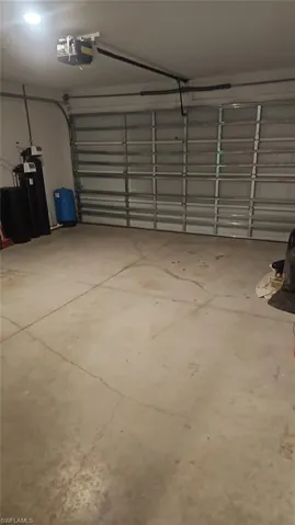 Integrated garage featuring a reinforced door, automatic opener, overhead lighting, and concrete flooring