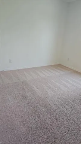 Neutral-toned carpeting featuring a visible pile pattern, complemented by light-colored walls and baseboards