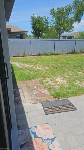 Paved patio area opening to a fenced backyard with a chain-link fence and privacy slats