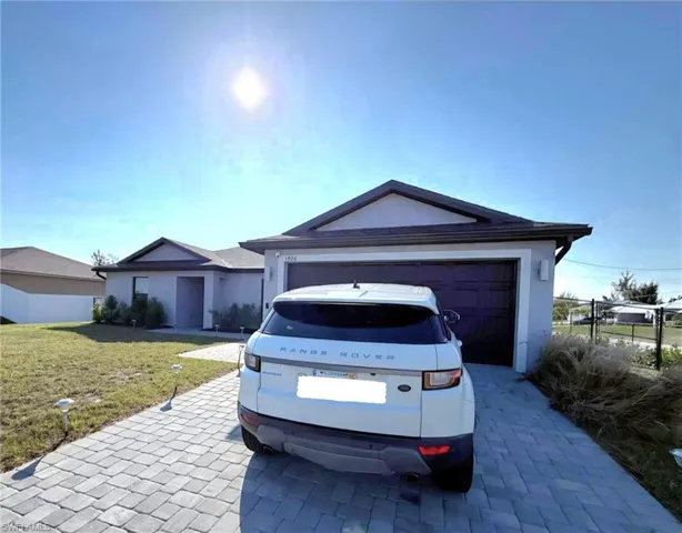 Ranch-style home featuring driveway, an attached garage, and stucco siding