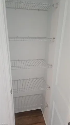 Vertical storage closet featuring four wire shelves and wood-finish flooring