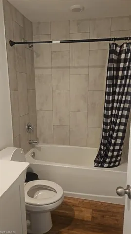 Bathroom featuring a white bathtub, ceramic tile surround, and wood-finish flooring